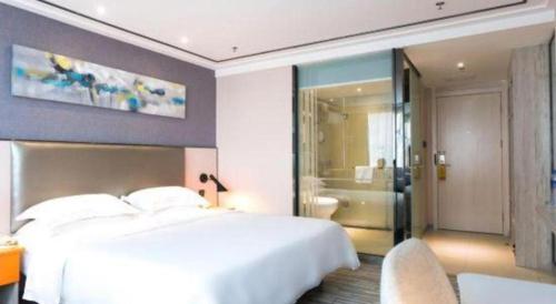 a bedroom with a large white bed and a bathroom at 7 Days Premium Zhuhai Gongbei Light Railway Branch in Zhuhai