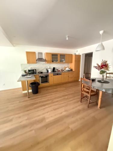 une cuisine avec des armoires en bois et une table et des chaises dans l'établissement L échappée verte - 6 voyageurs - 2 chambres, à Barr