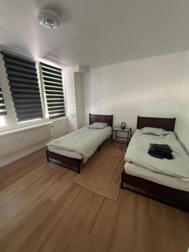 two beds in a room with wooden floors and windows at L échappée verte - 6 voyageurs - 2 chambres in Barr