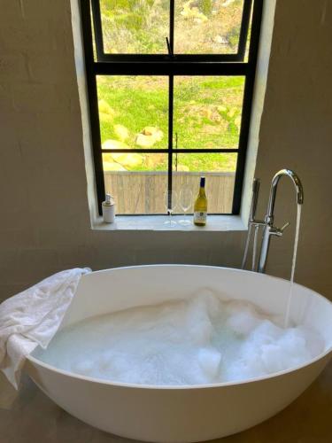 a bath tub filled with bubbles in front of a window at Arc Guest House in Cape Town