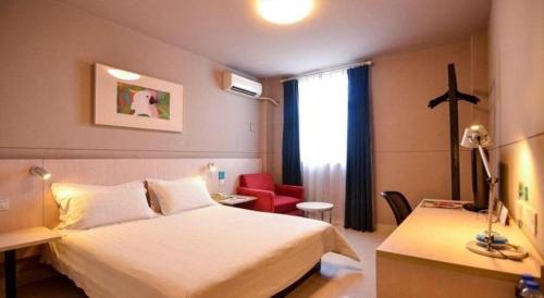 a hotel room with a white bed and a desk at Jinjiang Inn Luoyang Wangcheng Park Metro Station in Luoyang