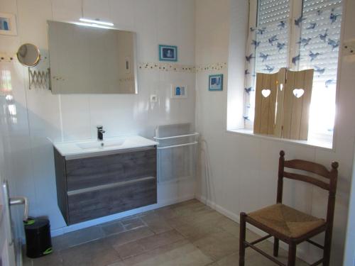 une salle de bain avec un lavabo, un miroir et une chaise dans l'établissement Villa Tournesol, à Bourdeilles