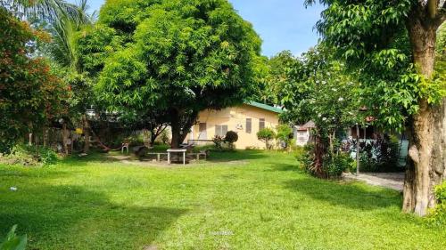 a yard with a house and a table and trees at Residencia del Mundo - Hotel in Puerto Galera