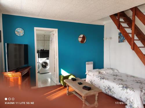 une chambre avec un lit et un mur bleu dans l'établissement Maison de vacances, à Dampierre-sous-Bouhy