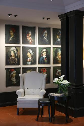a room with a white chair and a wall of portraits at Santa Maria Foris in Ravenna