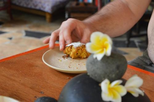 a person eating a piece of cake on a plate on a table at Namaste Yoga Farm in Gokarna