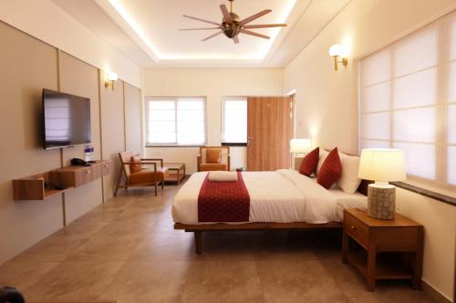 une chambre avec un grand lit avec un ventilateur de plafond dans l'établissement Arabian Pearl Beach Resort Cherai, à Cochin