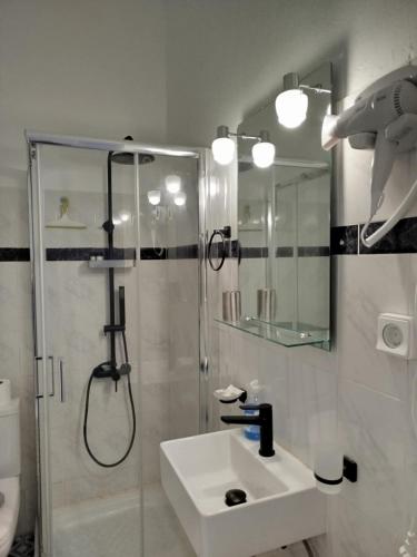 a white bathroom with a shower and a sink at Acheron rooms in Preveza