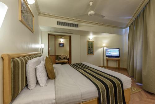 a hotel room with a large bed with a television at Comfort Inn President Near Ahmedabad Junction Station in Ahmedabad