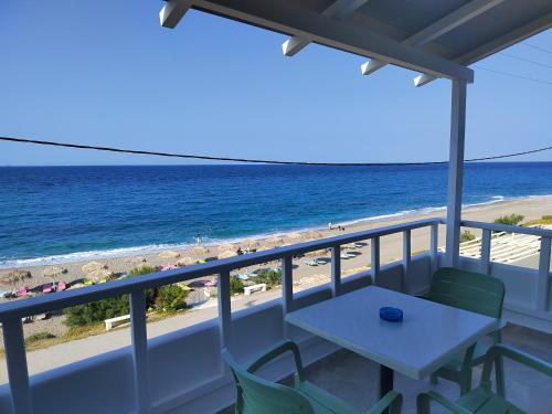 a balcony with a table and chairs and the beach at villa vagelis in Mourteri