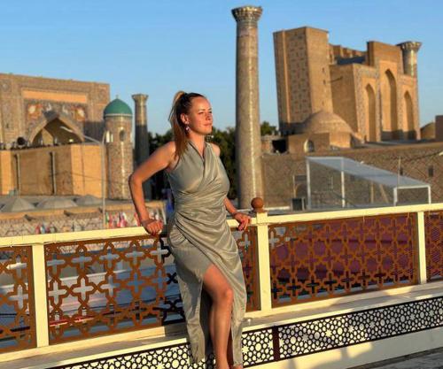 a woman in a dress standing next to a fence at Kamila & Terrace Boutique Hotel in Samarkand