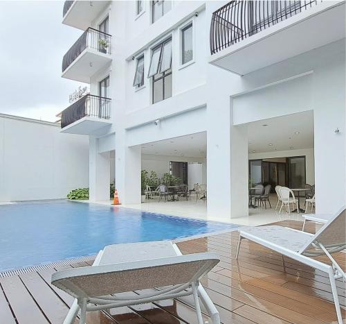 a white house with a swimming pool and chairs at W's Condo at One PonteFino Tower in Batangas City