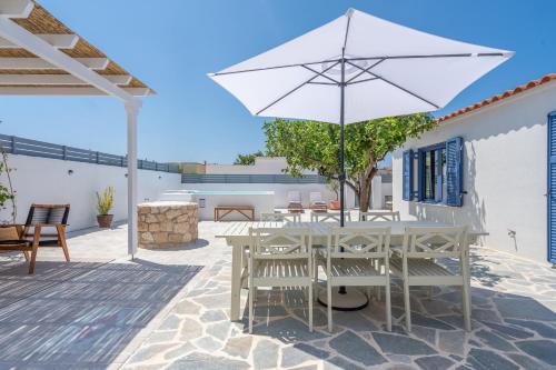 a patio with a table and a white umbrella at Koula's Aegina in Perdhika