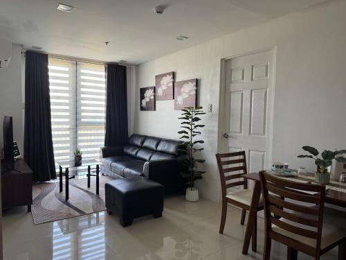 a living room with a black leather couch and a table at W's Condo at One PonteFino Tower in Batangas City