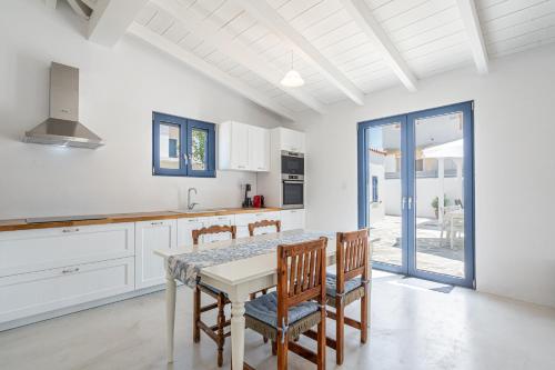 a white kitchen with a table and chairs at Koula's Aegina in Perdhika