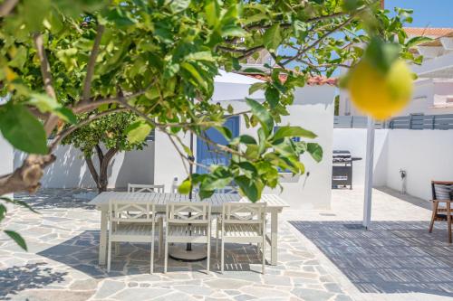 a table and chairs under a tree in a courtyard at Koula's Aegina in Perdhika
