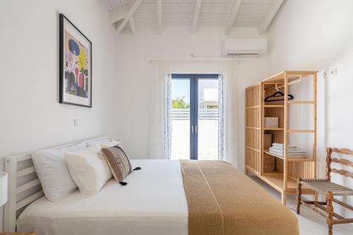 a white bedroom with a bed and a book shelf at Koula's Aegina in Perdhika