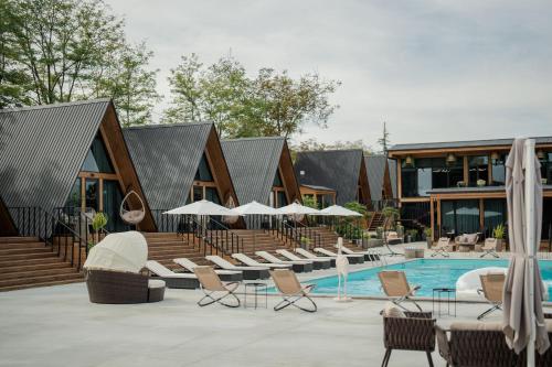 a pool with chairs and umbrellas next to a building at Ikalto Woods in Tʼelavi
