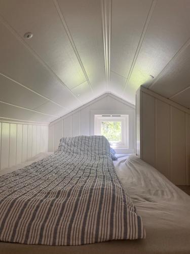 a large bed in a white room with a window at Koselig hytte nær sandstrand in Langenes