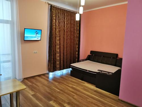 a bedroom with a bed and a tv on a wall at Apartment Avtorski Riviera in Fontanka