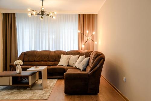 a living room with a brown couch and a table at Centar Komfor Apartment in Valjevo