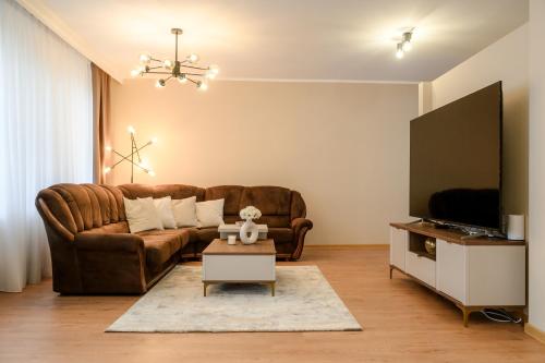 a living room with a brown couch and a tv at Centar Komfor Apartment in Valjevo