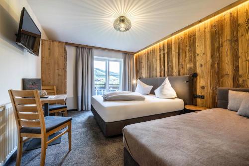 una camera d'albergo con due letti e una scrivania di Wechslerhof a Flachau