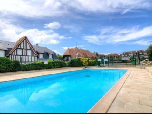 une piscine avec de l'eau bleue devant une maison dans l'établissement Studio Deauville PiscineTennisParking, à Deauville
