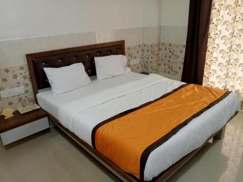 a bedroom with a large bed with an orange blanket at Via Sagar Residency in Navi Mumbai
