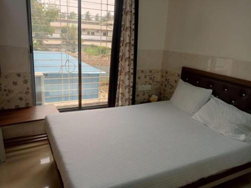 a bedroom with a bed with a large window at Via Sagar Residency in Navi Mumbai