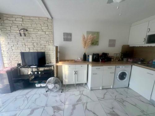 une cuisine avec des armoires blanches et une laveuse et une sécheuse dans l'établissement Évasion Soleil, Plage et Piscine, à Palavas-les-Flots