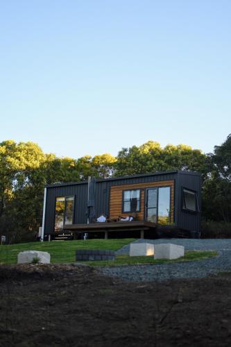 a black tiny house on a gravel lot at Milfarrago Farm Stay in Farnborough
