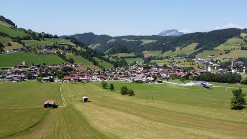 a green field with a village in the background at Hotel Der Wastlhof - Pools, Spa & eigene Reitschule in Niederau