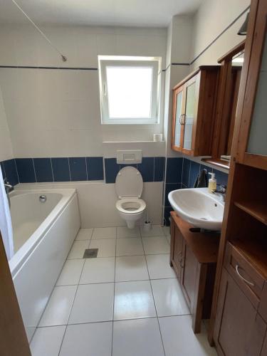 a bathroom with a tub and a toilet and a sink at Kristina Apartmanház in Dobrinj