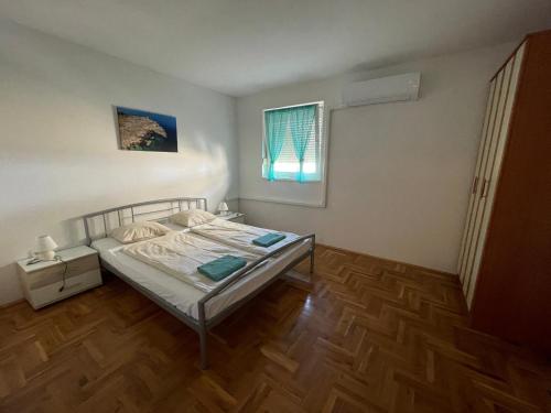 a small bedroom with a bed and a window at Kristina Apartmanház in Dobrinj