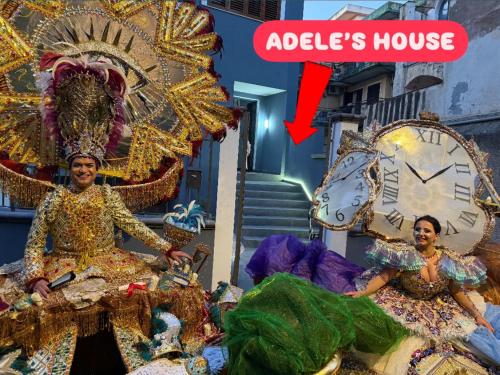 two women in elaborate costumes sitting next to a clock at Adeles house in Misterbianco
