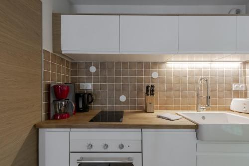 une cuisine avec des armoires blanches et un évier dans l'établissement Le Montagnard, à Saint-Gervais-les-Bains