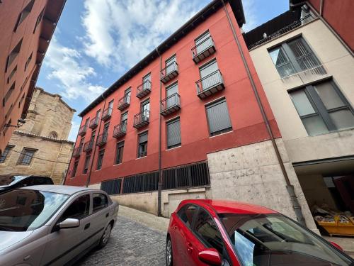two cars parked in front of a red building at Piso 3 habitaciones Tranquilo y Céntrico in Navarrete