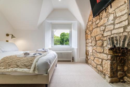 2 Bedroom Cottage-Free Parking في Newtongrange: غرفة نوم بسرير وجدار حجري