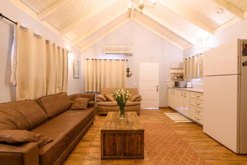 a living room with a couch and a table at בקתות ילוז של רשת לב הגולן - 6 צימרים מקסימים עם בריכה משותפת ליד הכנרת in Yavneʼel