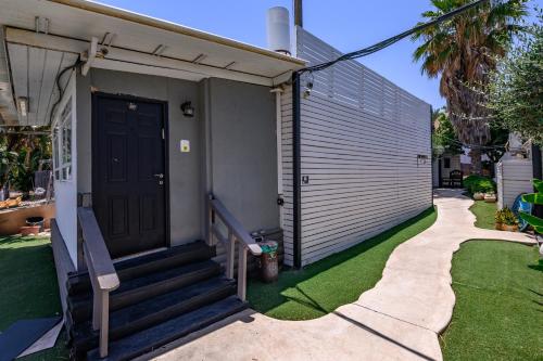 a house with a black door and a yard at בקתות ילוז של רשת לב הגולן - 6 צימרים מקסימים עם בריכה משותפת ליד הכנרת in Yavneʼel