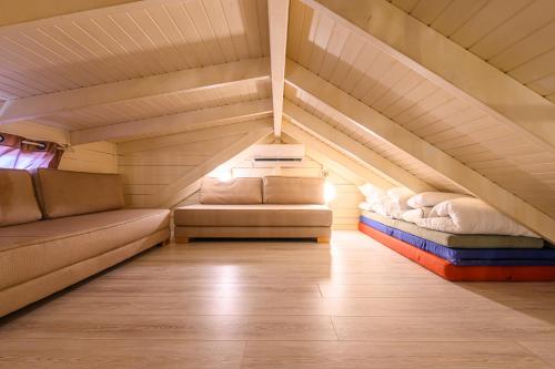 a room with two beds and a couch in a attic at בקתות ילוז של רשת לב הגולן - 6 צימרים מקסימים עם בריכה משותפת ליד הכנרת in Yavneʼel