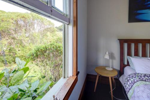 a bedroom with a window with a bed and a table at Te Kōpuha in Tora