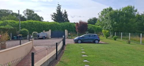 a blue car parked in a yard next to a fence at Chambre d'hôtes La Clé du Bonheur in Manthelon
