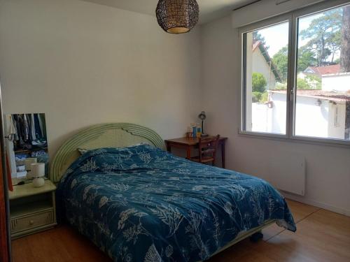 une chambre avec un lit avec une couette bleue et une fenêtre dans l'établissement Maison au calme, à Saint-Brévin-les-Pins