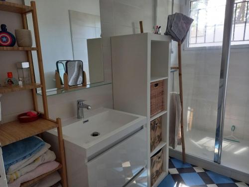 une salle de bain blanche avec un lavabo et une douche dans l'établissement Maison au calme, à Saint-Brévin-les-Pins