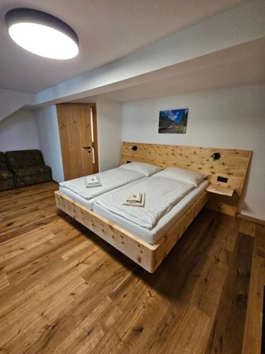 a large bed in a room with a wooden floor at Landhotel Lacknerhof in Mariapfarr