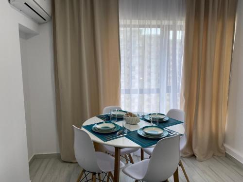 a dining room table with white chairs and a window at Olimp sea view apartments - 802 in Olimp