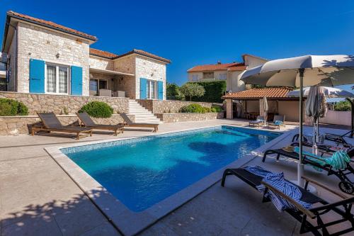 a swimming pool with two chairs and an umbrella at Villa Augusta in Malinska