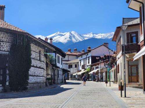eine Person, die eine Straße mit Bergen im Hintergrund entlang geht in der Unterkunft Trinity Apartment & Pool with Spa Near Center in Bansko